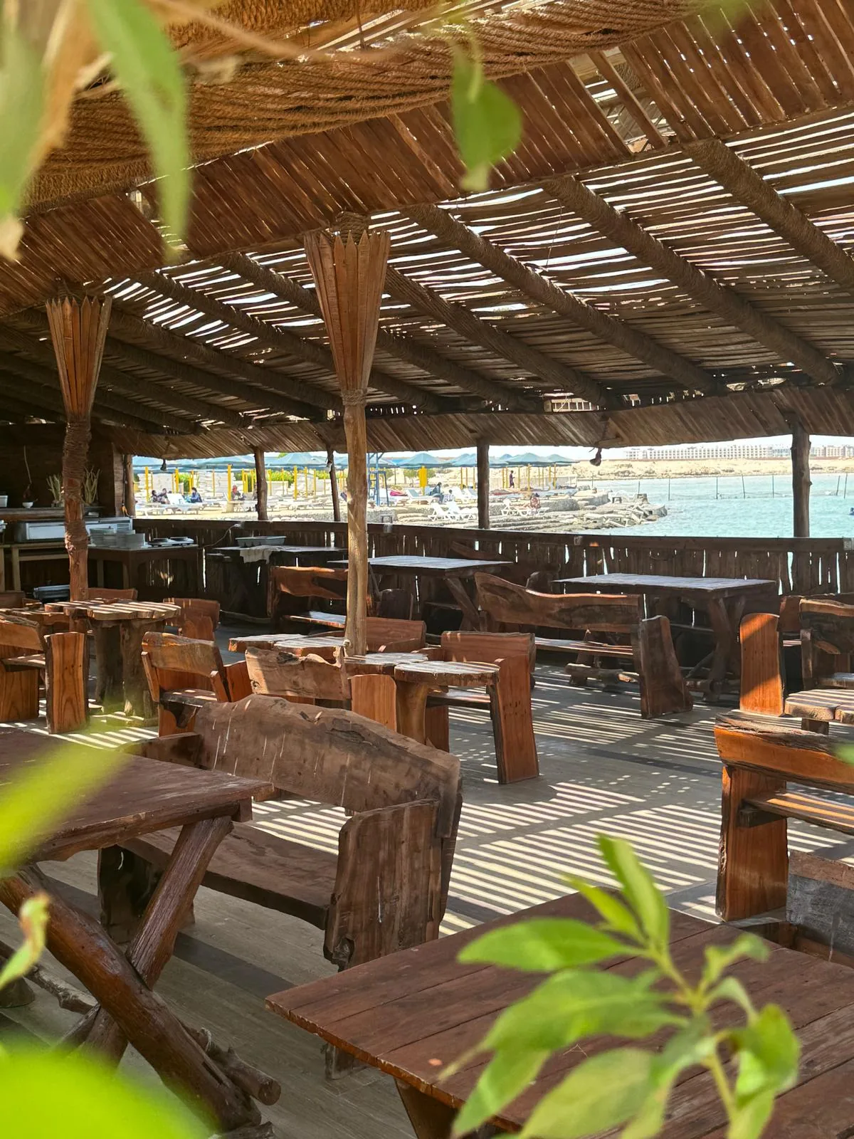 Tables en bois au restaurant DaVinci Beach donnant sur la plage privée et la mer Rouge à Hurghada